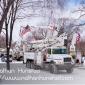 Several flags hang from cherry pickers as one drives off