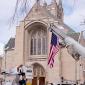 A flag hangs from a cherry picker in front of the House of Hope Presbyterian Church on Summit Avenue