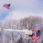 Two flags fly, one from a flagpole, one from a cherry picker