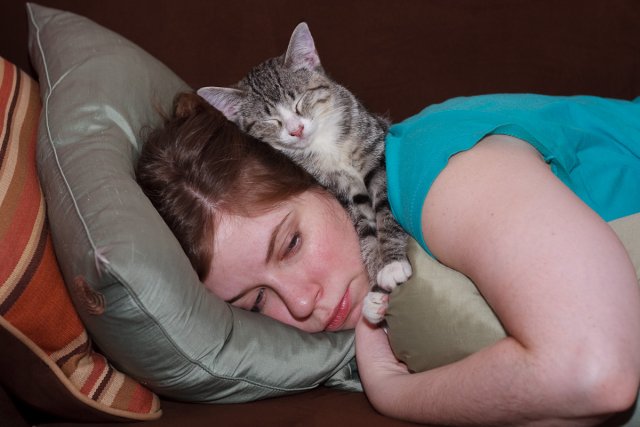 Julia Miller lying on the couch while Sasha sleeps on top of her.
