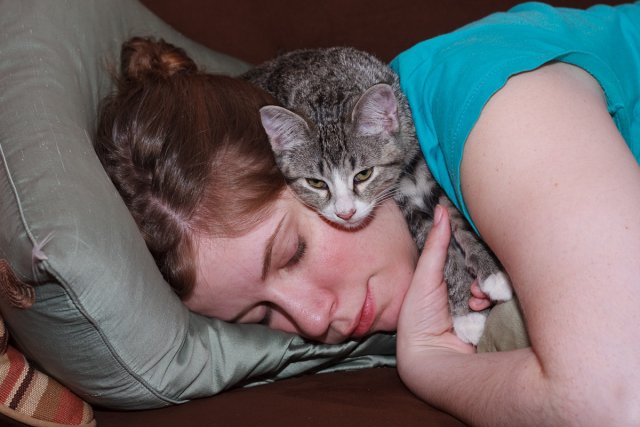 Julia Miller lying on the couch while Sasha lies on top of her.